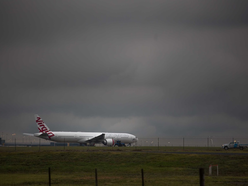 A storm cloud looms over Virgin plane near the runway at Melbourne airport