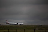 A storm cloud looms over Virgin plane near the runway at Melbourne airport