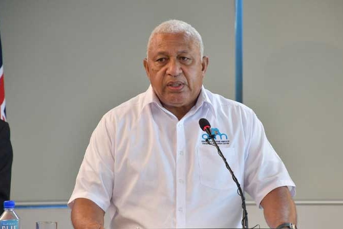 Wide shot of a man standing and speaking at a podium.