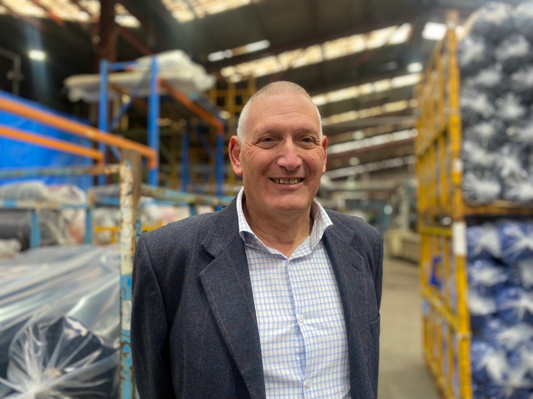A man in a suit stands in a factory.