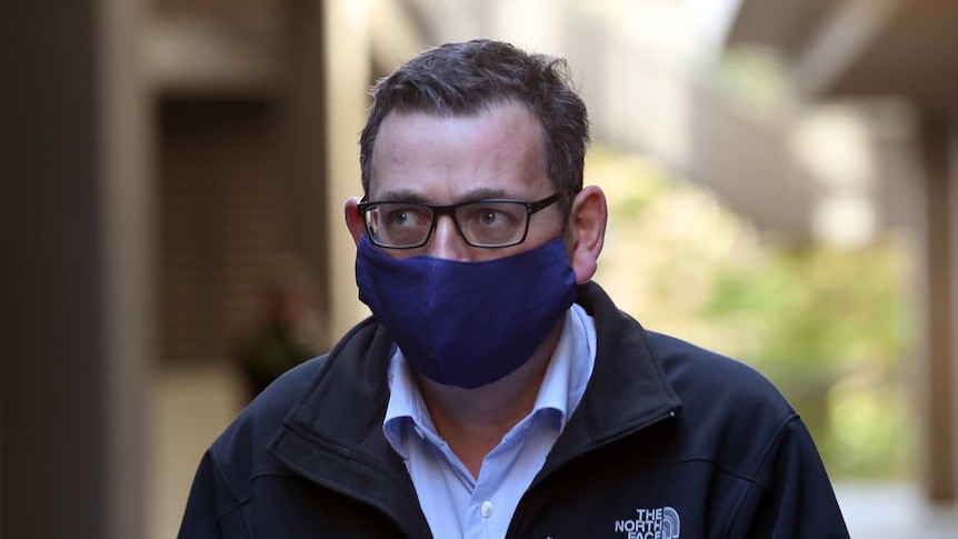 Daniel Andrews wears a blue face mask.