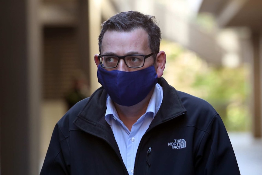 Daniel Andrews wears a blue face mask.