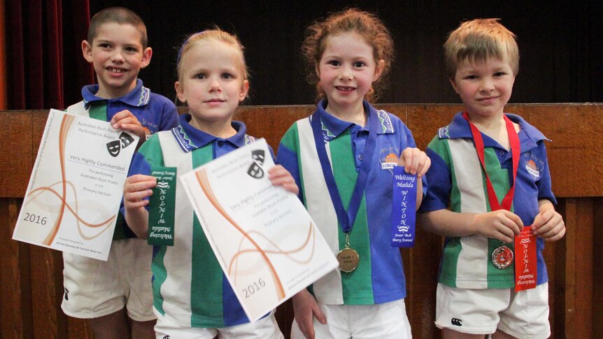 Four children with awards smile at the camera.