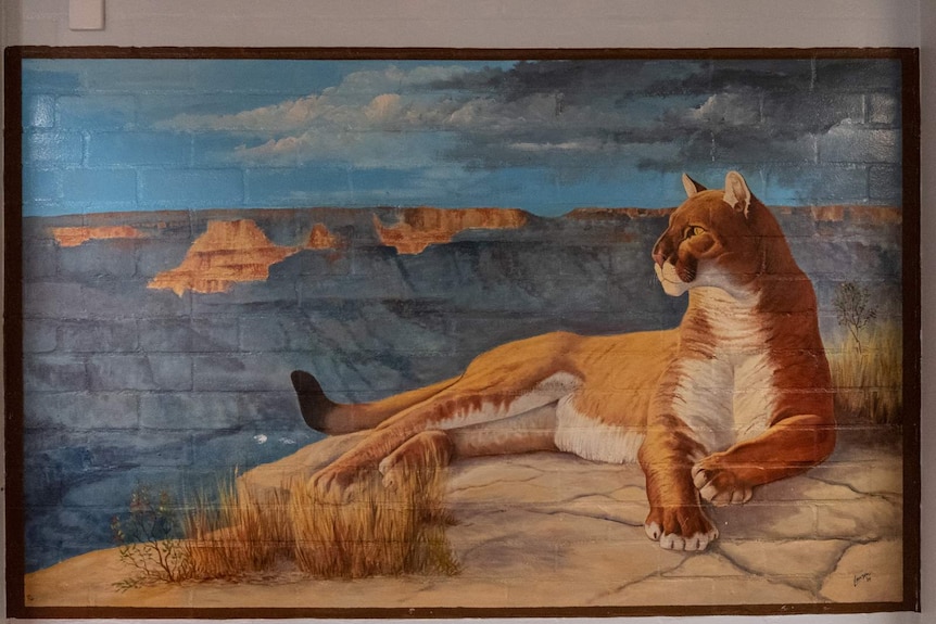 Painting of lion with rocky cliffs in background
