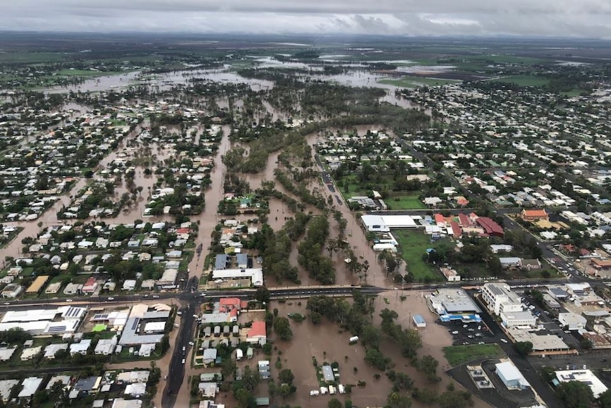 Brown flood water through the streets of a country town, pictured from above