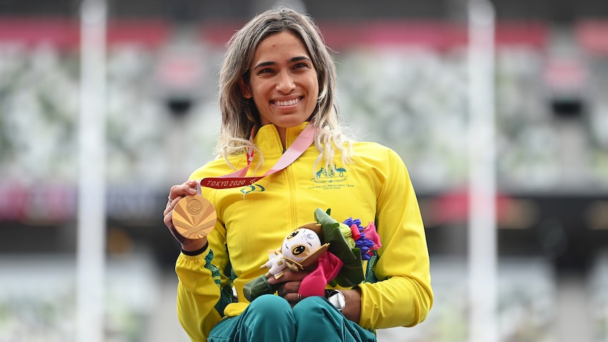 Paralympian smiling with her gold medal at the medal ceremony