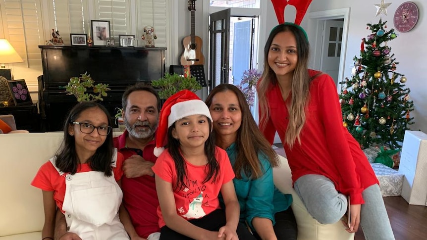 A family of five smiling at the camera on a couch.