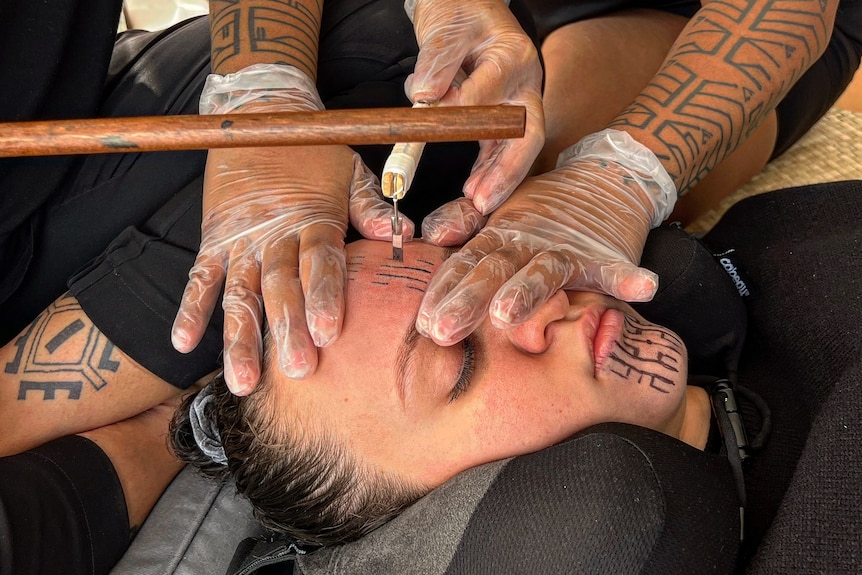 A traditional tattooing method is applied to a woman's face