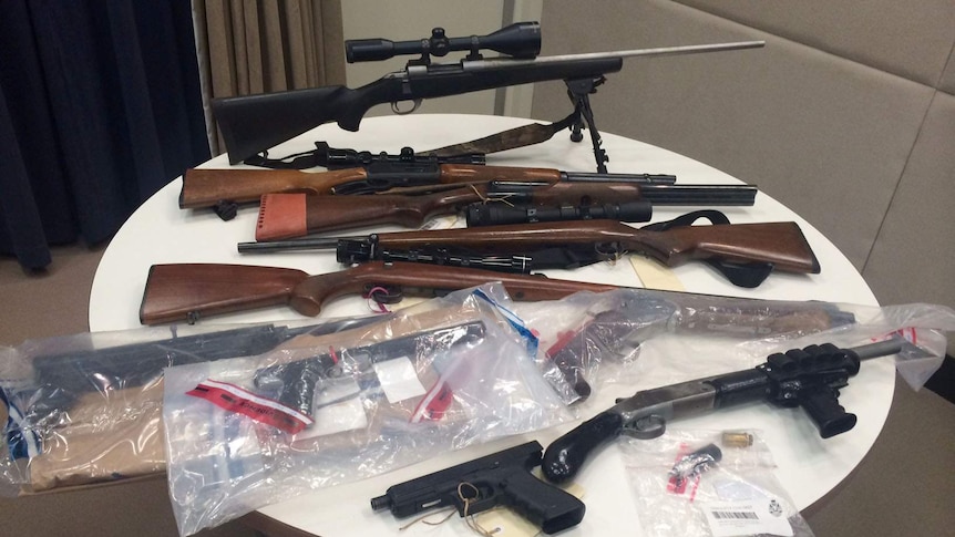 Seized firearms displayed on a table.