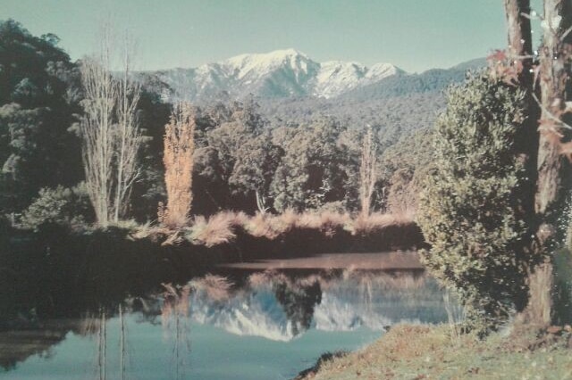 A beautiful dam with snow-capped mountains in the background.