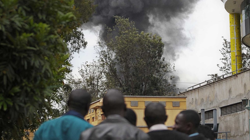 People look on as smoke billows from the Westgate shopping mall in Nairobi as a siege drags on.