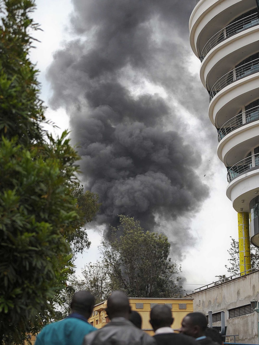 People look on as smoke billows from the Westgate shopping mall in Nairobi as a siege drags on.