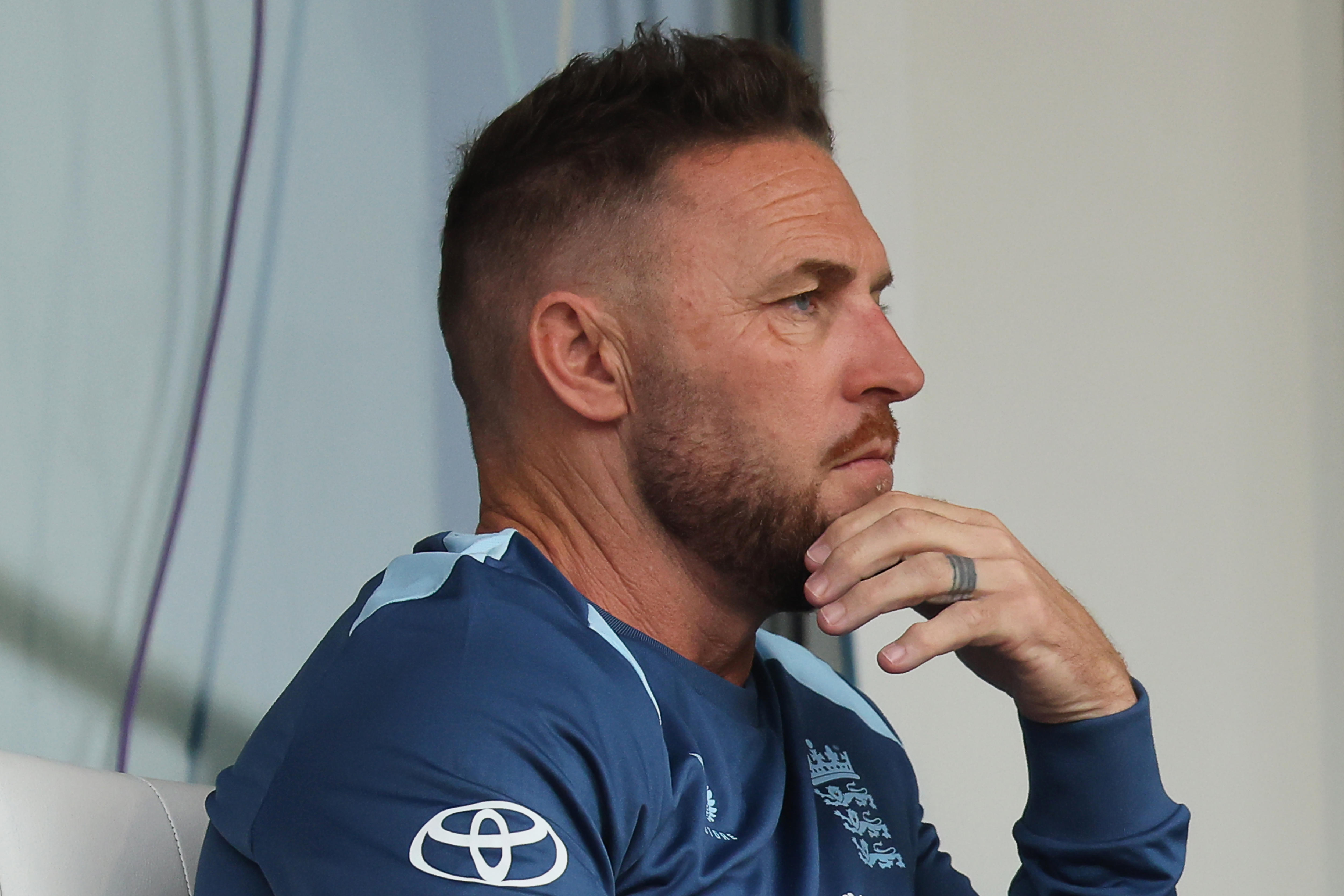 Brendon McCullum holds his chin. Watches seriously.