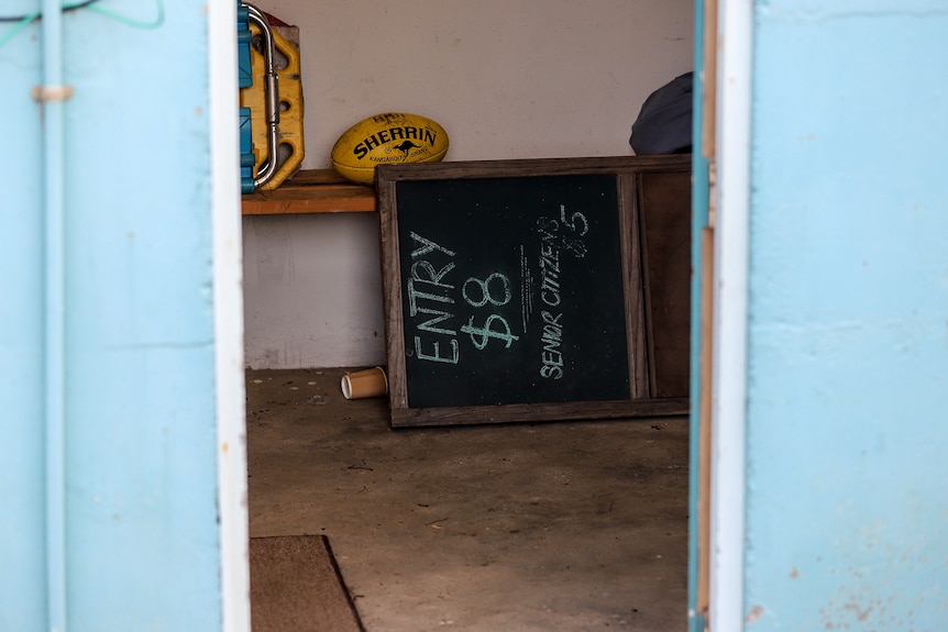 A chalkboard sign on its side in a concrete room advertising entry costs for senior citizens