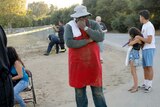 A group pf people stand outside one is a man with his hand on his chin and arms folded