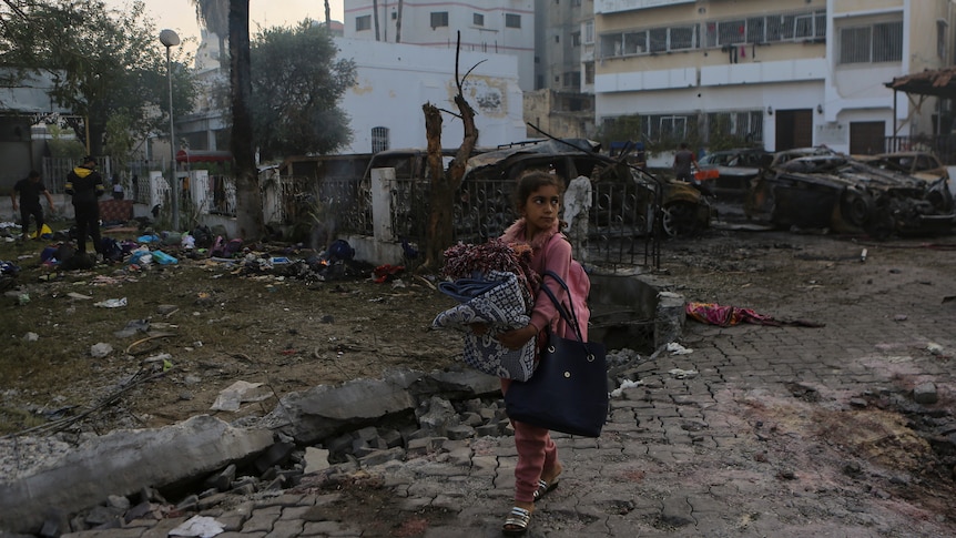 A gir walks through an area with destruction shown behind her.