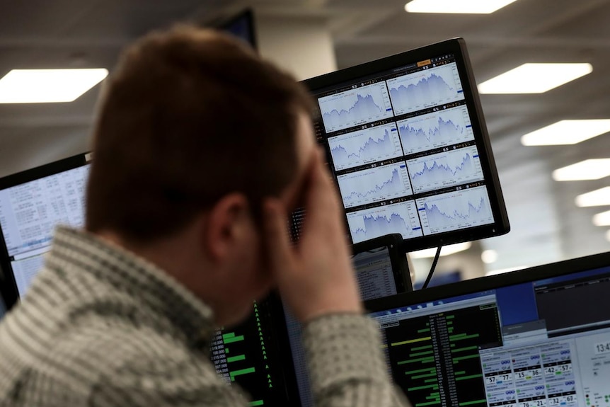 A trader looks at financial information on computer screens on the IG Index the trading floor in London