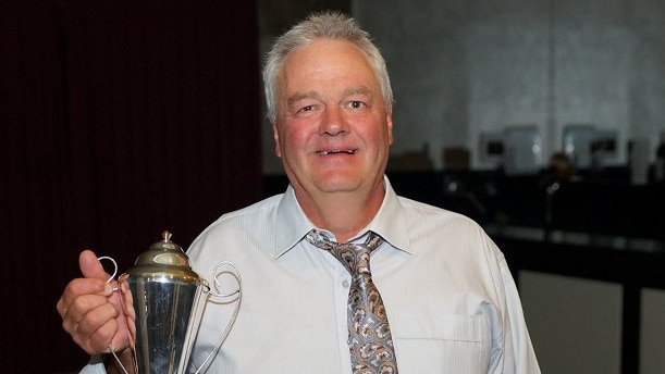 a man wearing a white shirt and a tie, holding a trophy