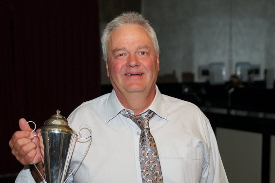 a man wearing a white shirt and a tie, holding a trophy