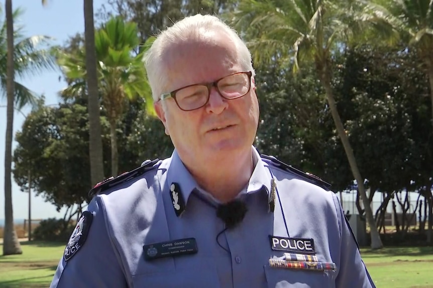A police officer in a blue shirt and grey hair.