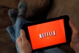 a person displays Netflix on a tablet