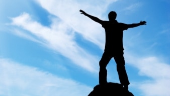 Silhouetted man on peak of mountain