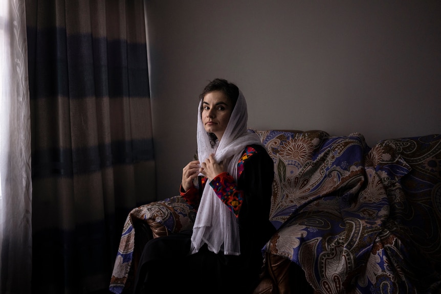 Asita Ferdous sitting on a coach inside her home looks at the camera 