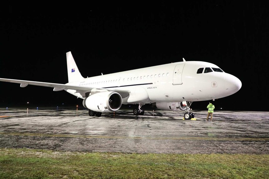 A white plane on the tarmac at night.