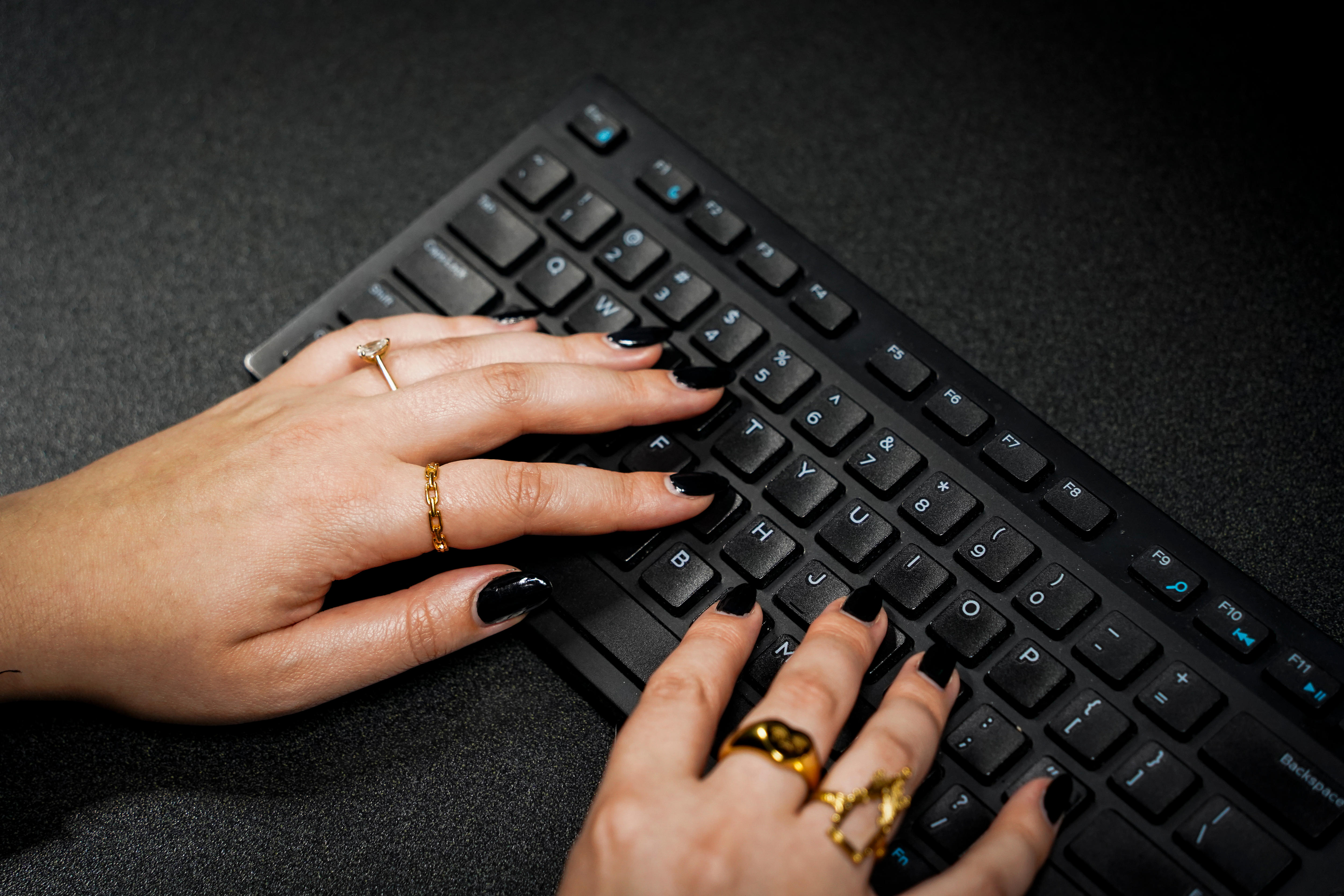 A woman's fingers typing on a computer keyboard. 