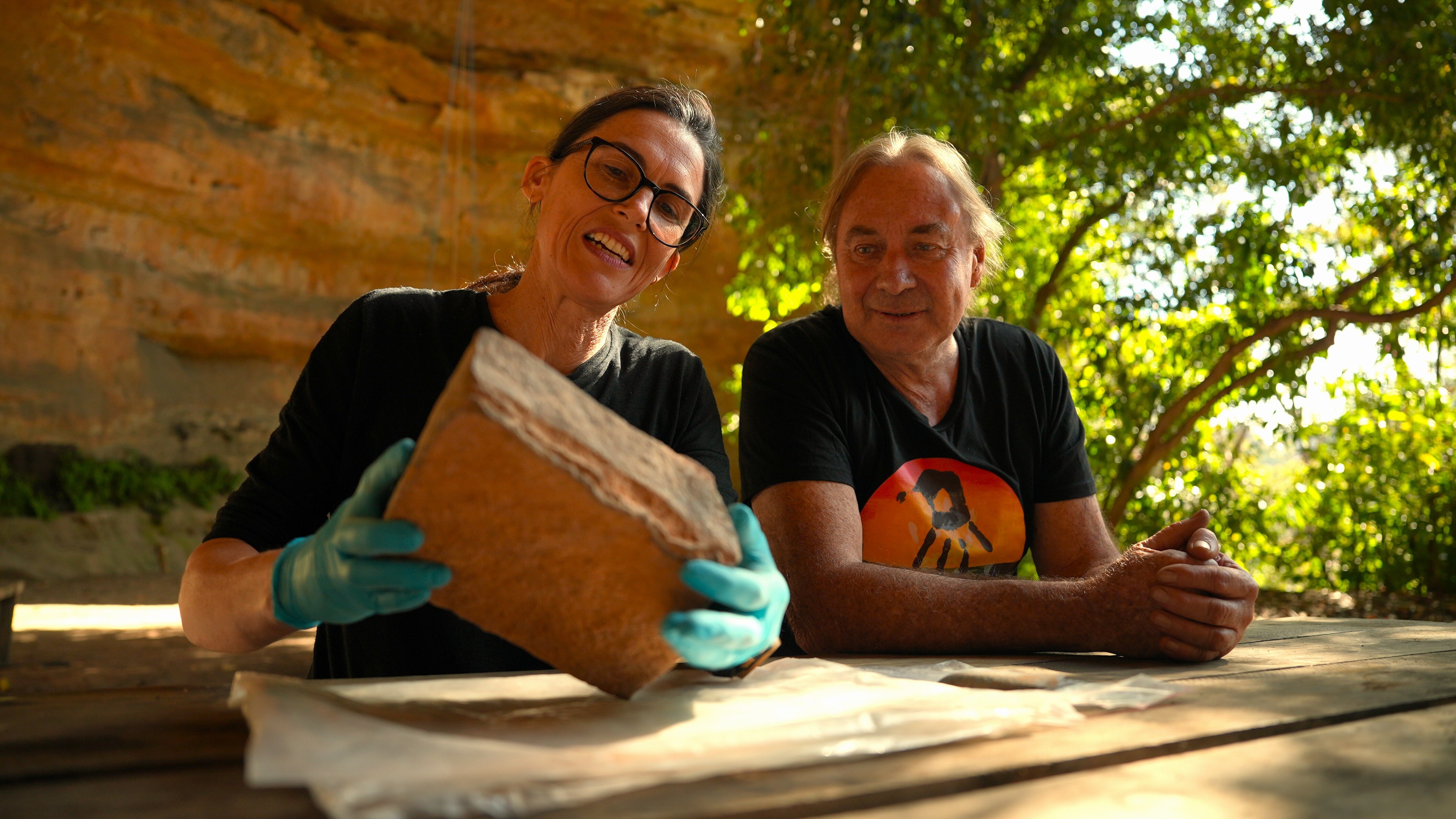 A woman and man look at a piece of stone.