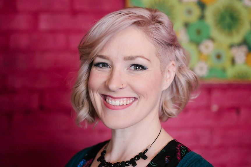 A woman with blonde hair smiles at the camera.