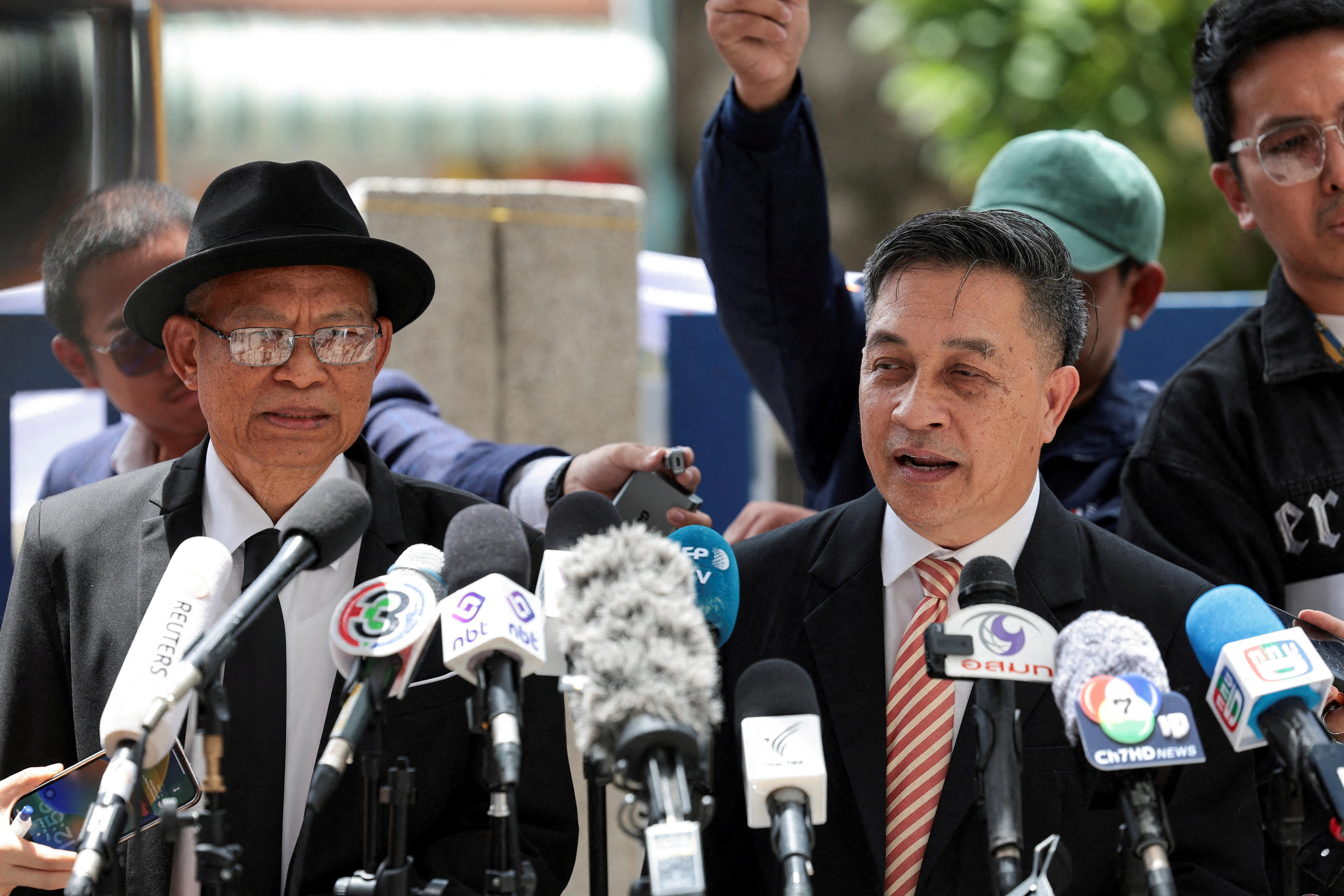 Two older men in business attire stand in front of mics outside a courthouse