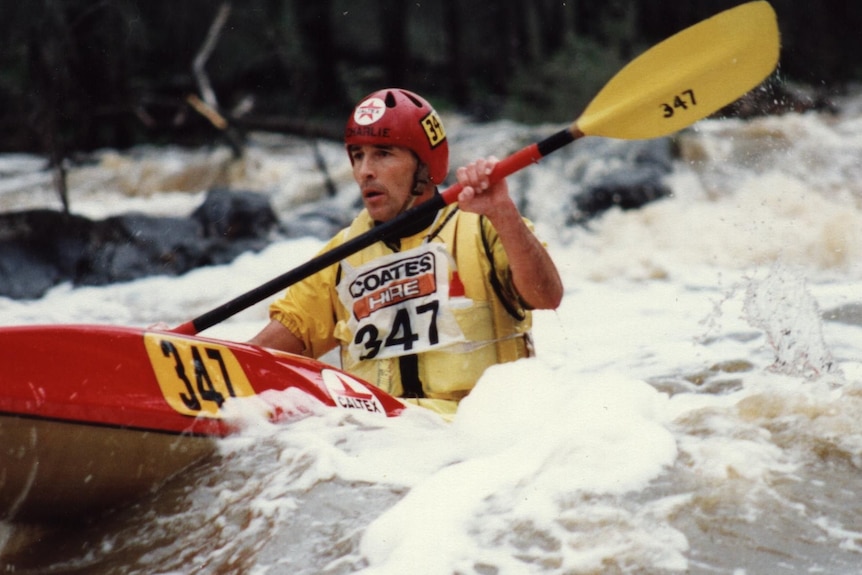 An old photo of Charlie in a kayak, traversing the whitewater rapids.