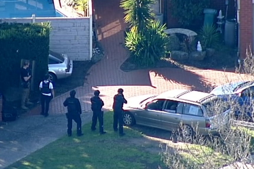 An aerial shot of police dressed in flak jackets standing outside a home.