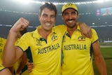 Two male cricket players in Australia kit embrace and celebrate.