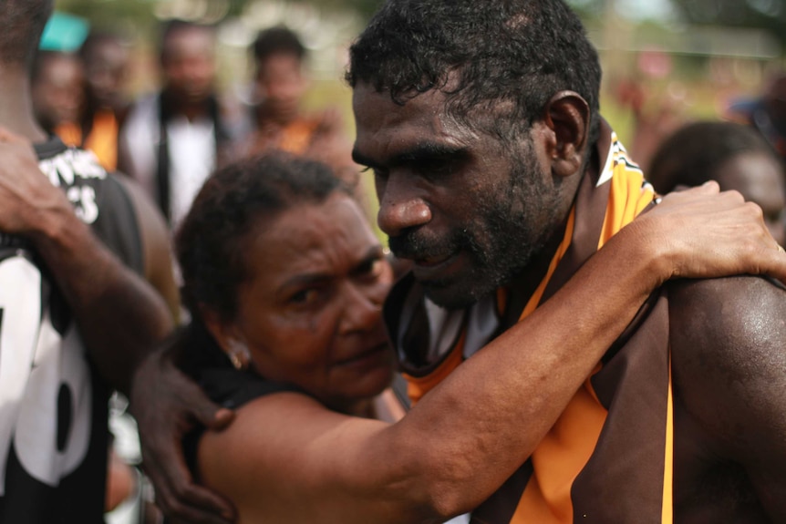 A mother hugs her son after his team loses the Tiwi football grand final.