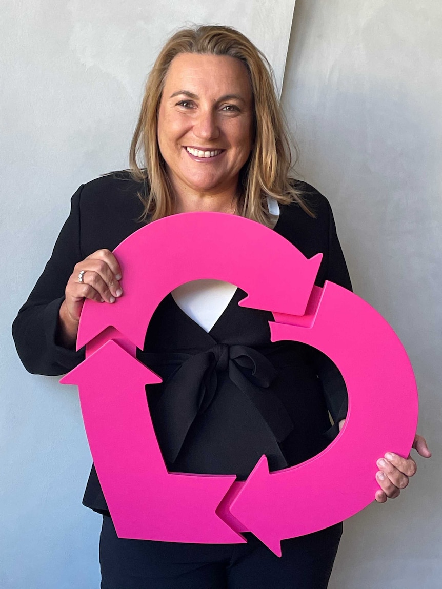 Lucinda holds a sign representing organ donation. smiling.