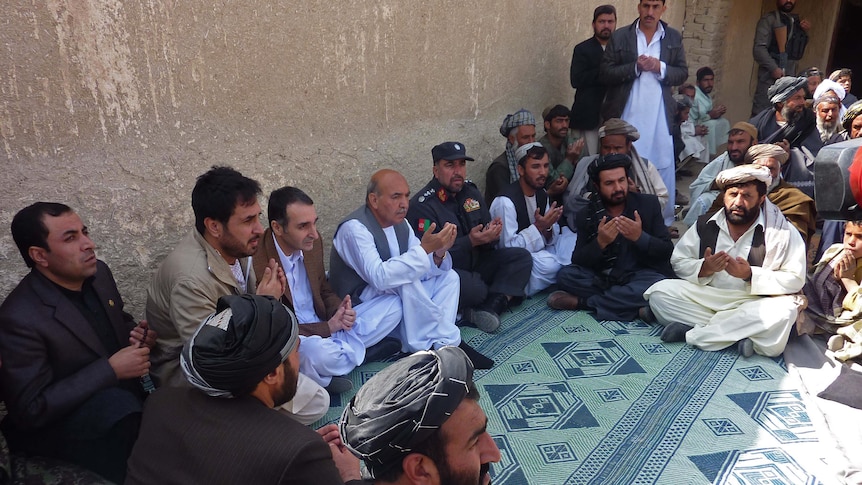 Afghan men pray for killing spree victims