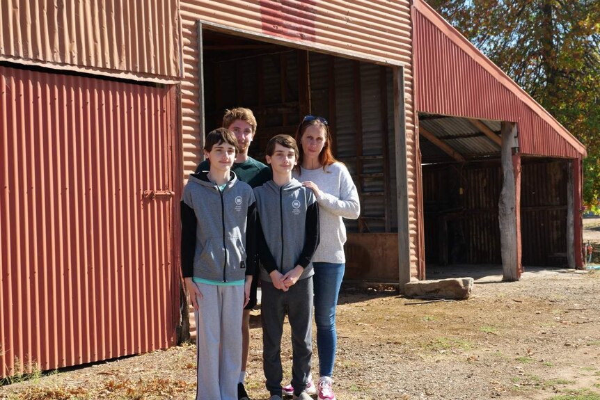 A family stands outside a red barn