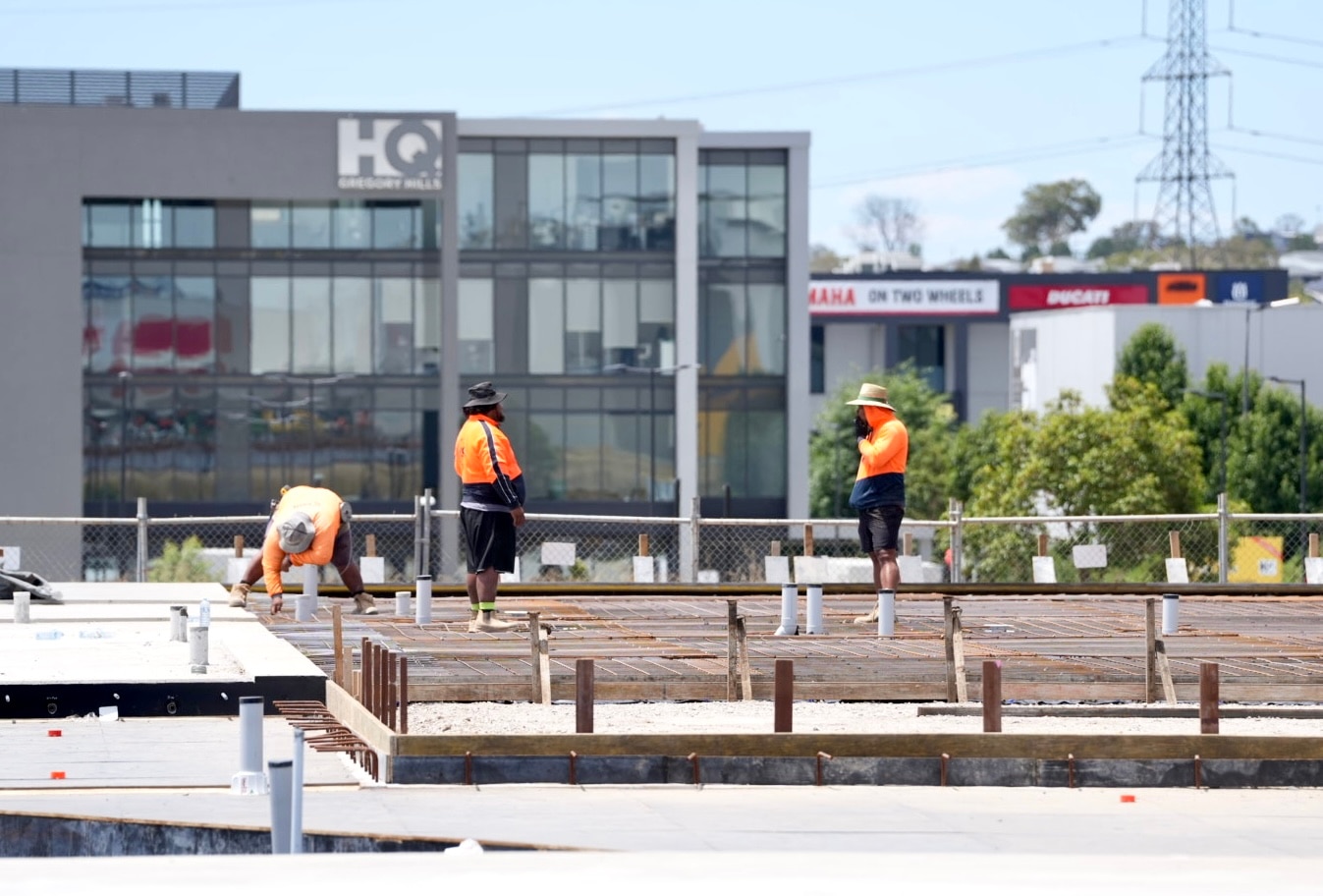 Dos trabajadores de la construcción con ropa de alta visibilidad están parados sobre una losa de concreto.
