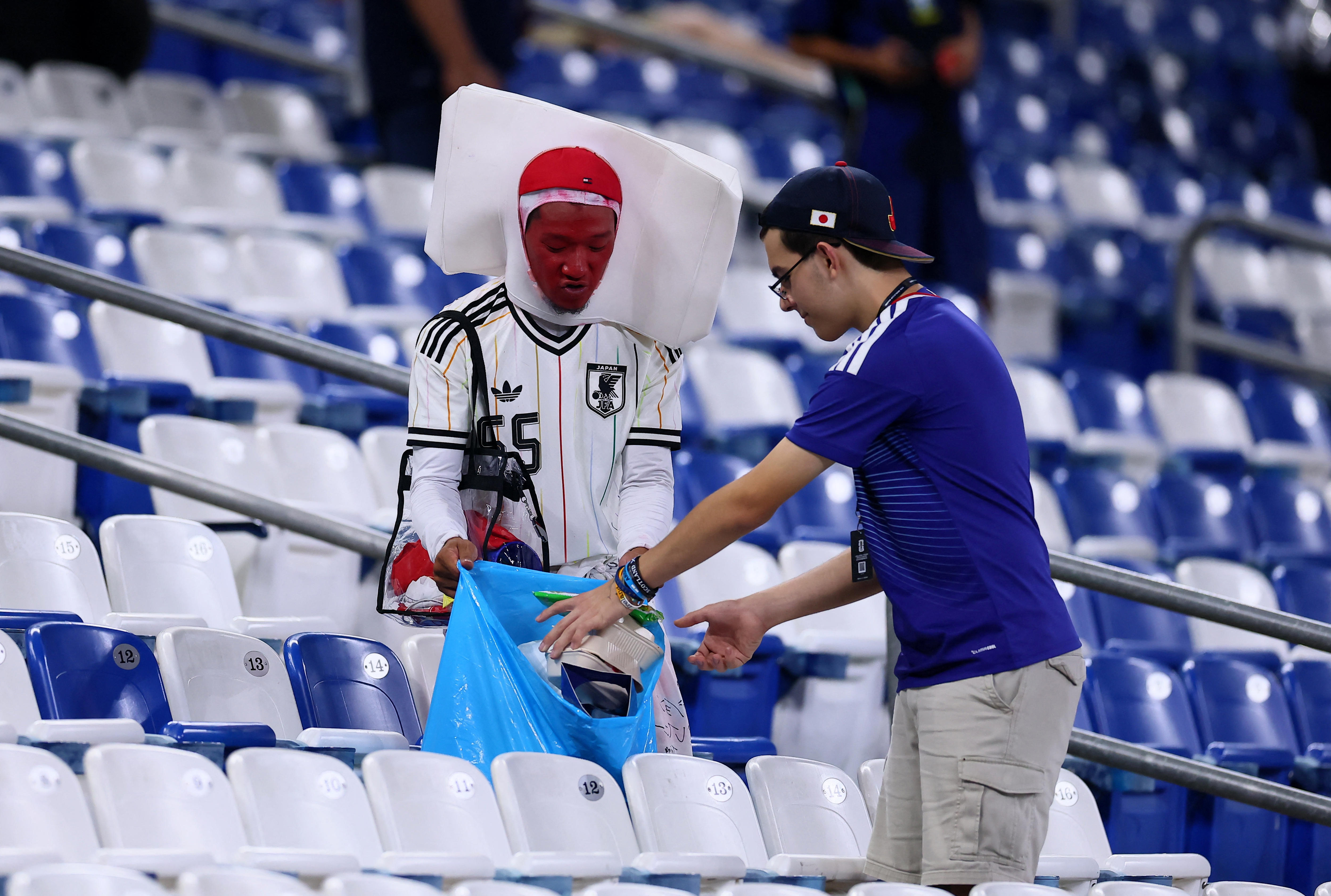 Two Japan fans, one dressed as the Japanese flag, clean up rubbish