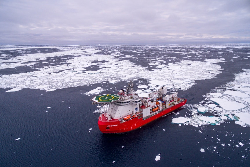 Aerial view of a red icebreaker travelling through the ocean after having broken through ice.