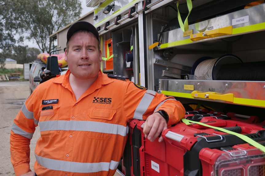 A man leaning on an emergency vehicle wearing an SES uniform  