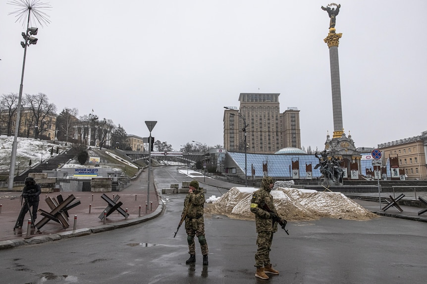 Ukrainian military members stand guard at Independence Square, in Kyiv with large guns
