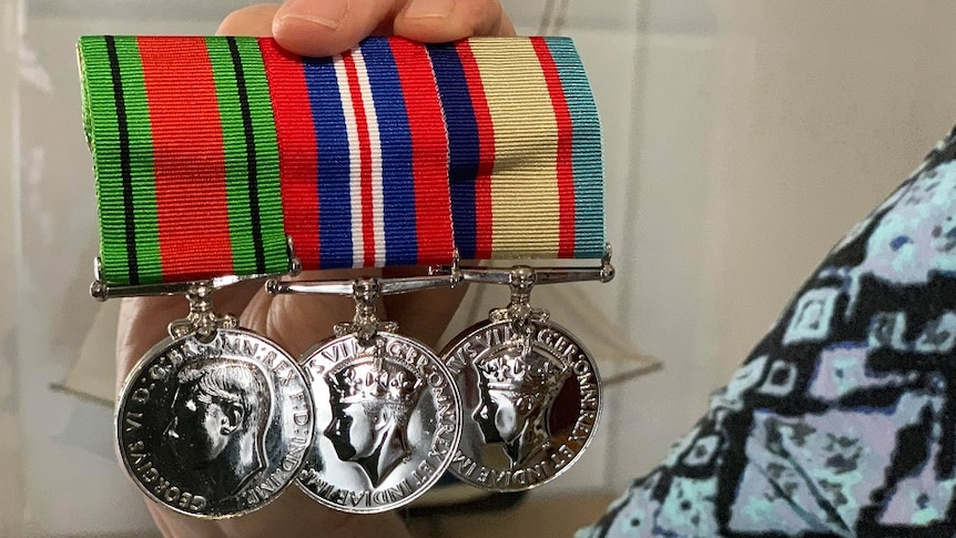 A woman's hand holds three war medals