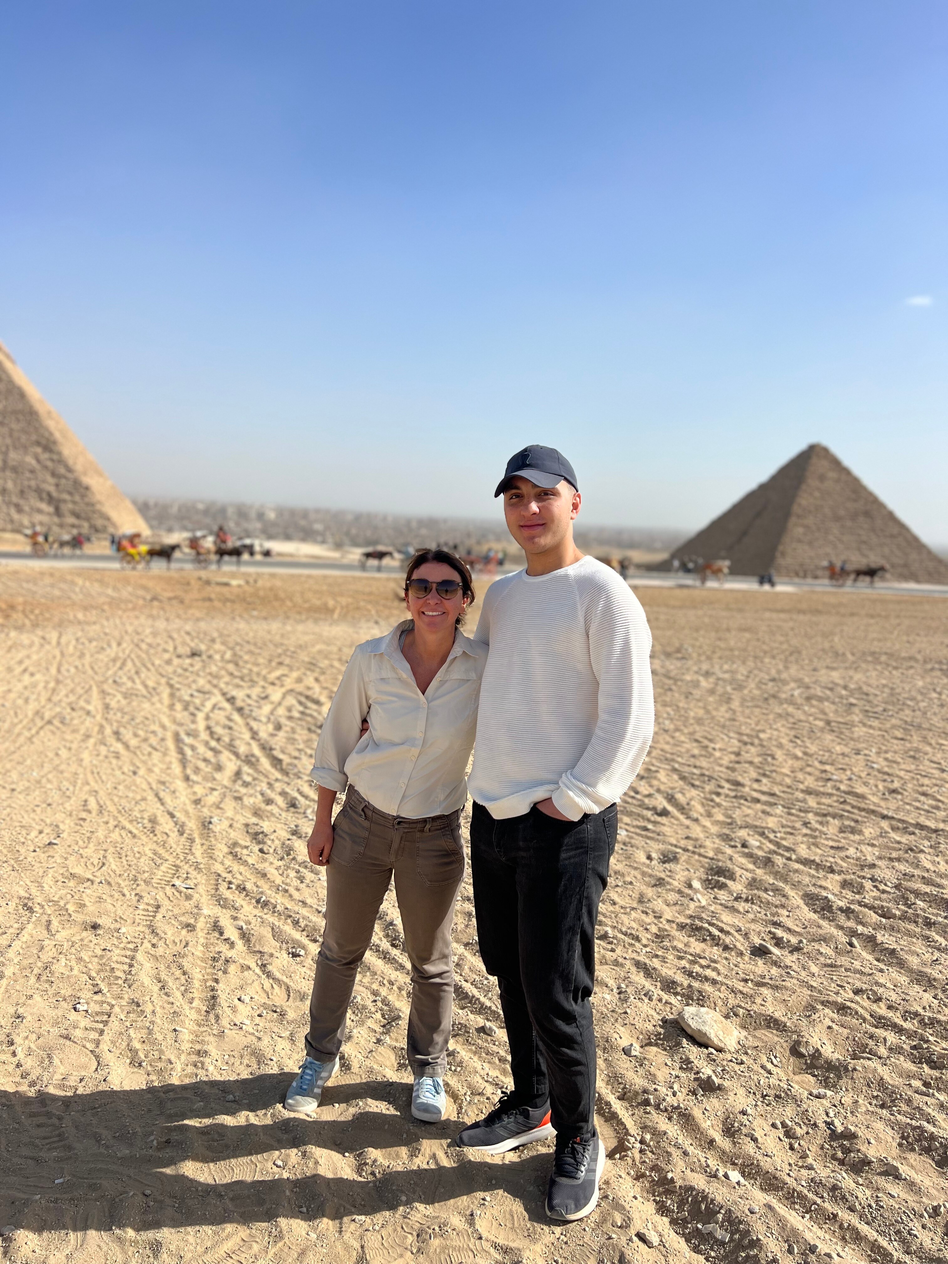 A woman stands next to a man with pyramids behind them.