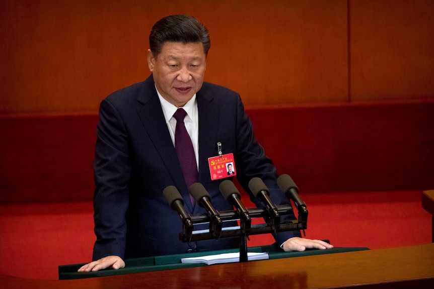 Chinese President Xi Jinping speaks into microphones at a podium.