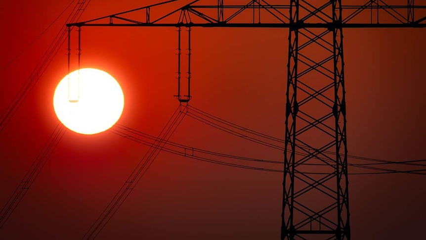 A power pylon with a bright sun in the background.