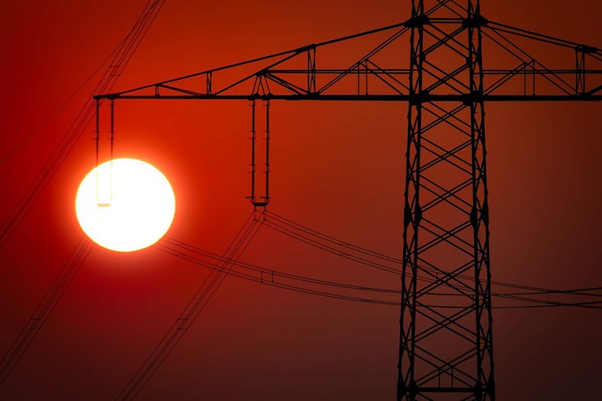 A power pylon with a bright sun in the background.