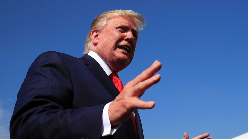 Donald Trump, pictured from below, as he speaks and gestures with his hands.